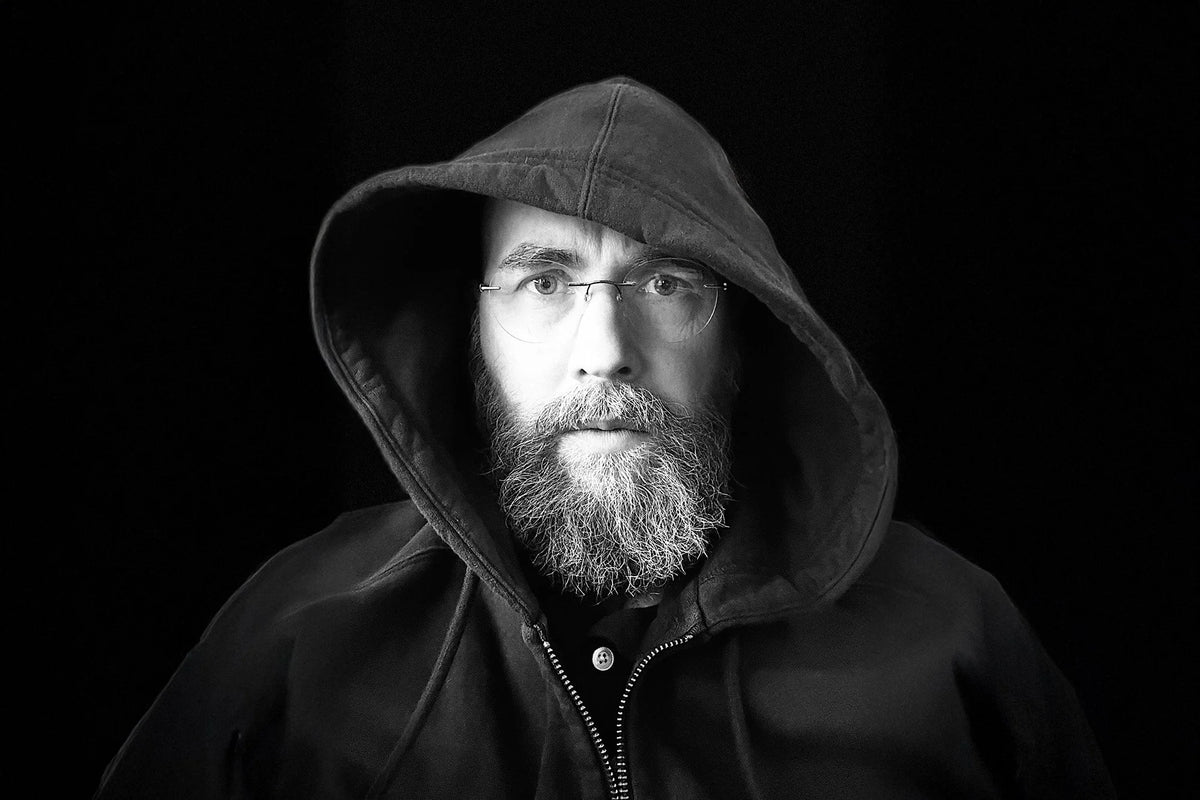 Author Ben Wakeman  wearing a hooded jacket against a black background