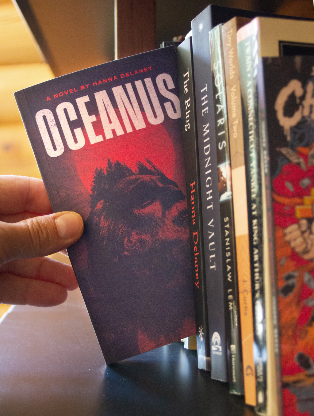 Book titled 'Oceanus' held by a hand with other books in the foreground